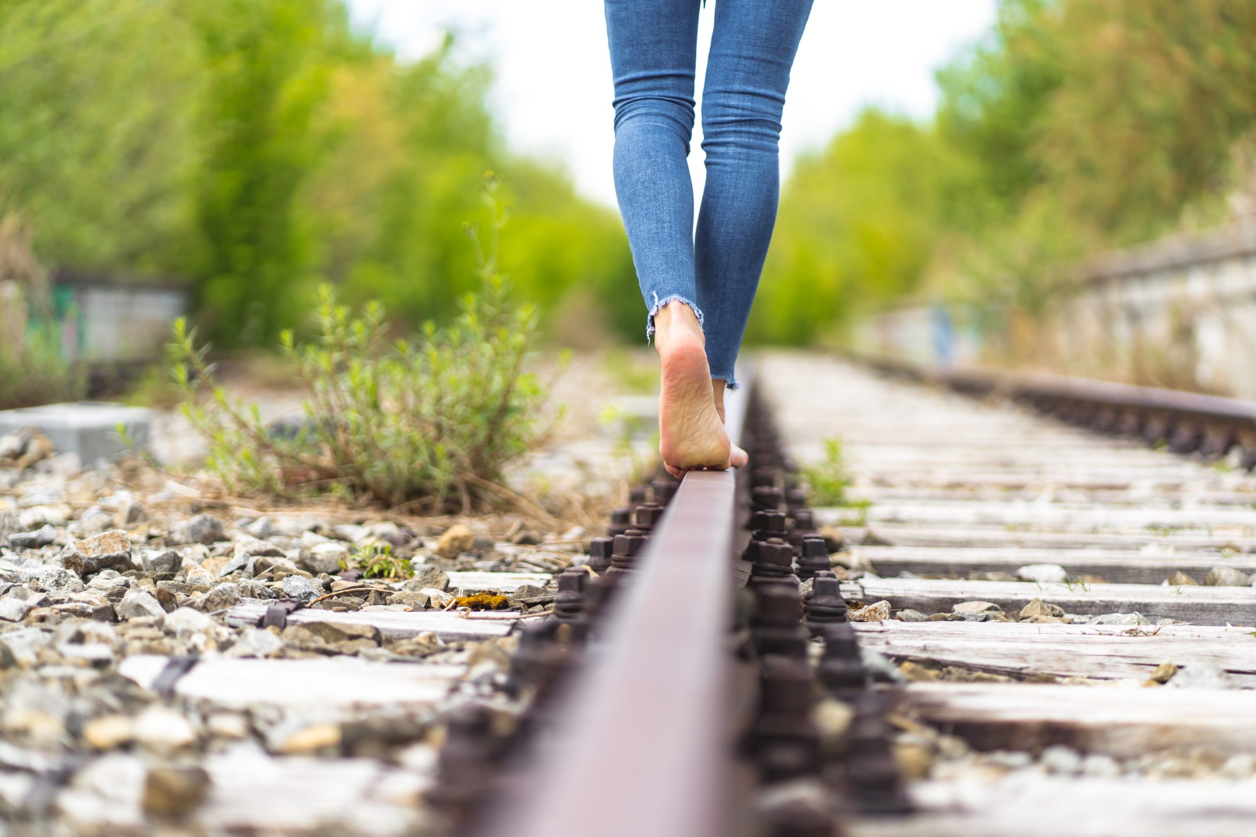 Female in jeans walking through the train rails barefoot A female in jeans walking through the train rails barefoot